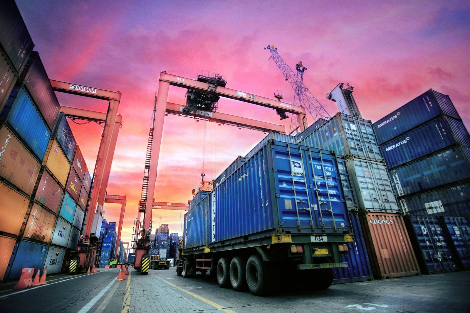 Shipping containers stacked at a port at sunset